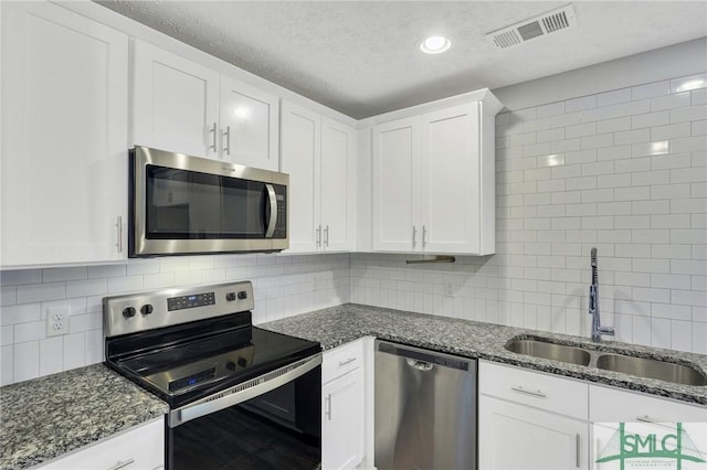 kitchen featuring white cabinetry, stainless steel appliances, sink, and dark stone countertops