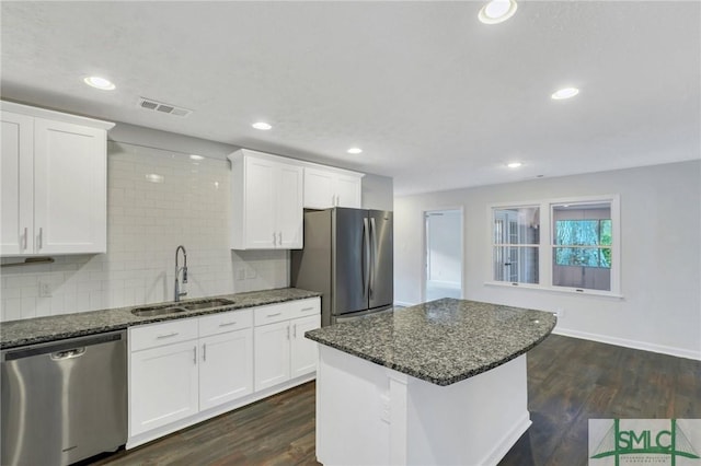 kitchen featuring sink, stainless steel appliances, a center island, white cabinets, and dark stone counters