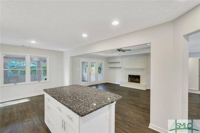 kitchen with white cabinetry, dark stone counters, a center island, and a wealth of natural light