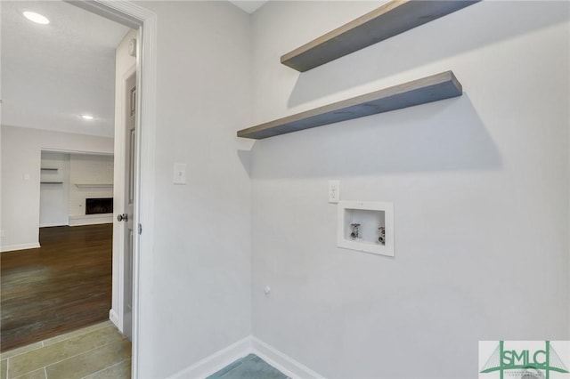 clothes washing area featuring hardwood / wood-style floors, washer hookup, and a fireplace