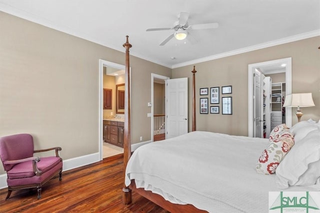 bedroom with crown molding, a walk in closet, ensuite bath, dark hardwood / wood-style flooring, and ceiling fan