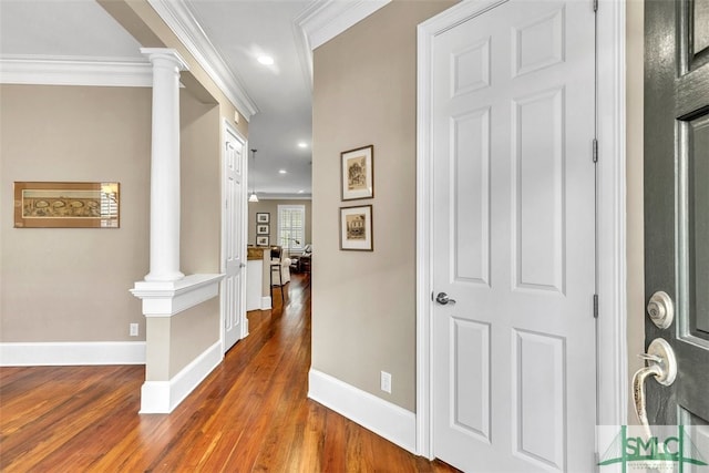 hallway with decorative columns, ornamental molding, and wood-type flooring