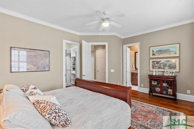 bedroom featuring crown molding, dark wood-type flooring, ensuite bathroom, and a spacious closet