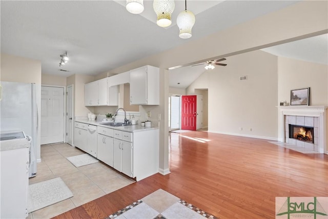 kitchen featuring sink, white appliances, light hardwood / wood-style flooring, white cabinets, and decorative light fixtures