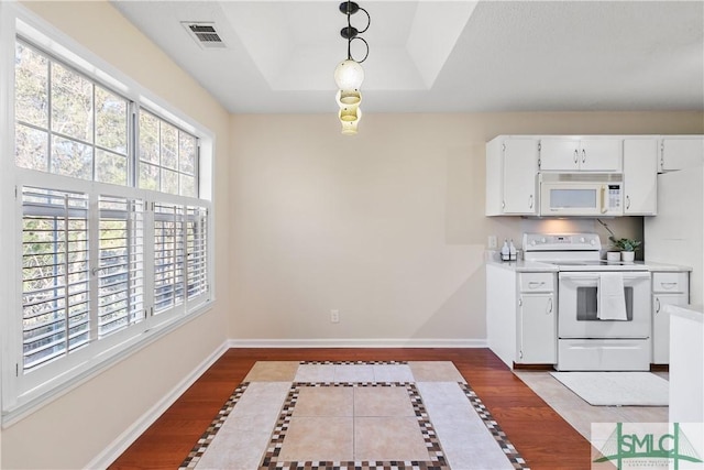 kitchen with white cabinetry, hanging light fixtures, dark hardwood / wood-style floors, a raised ceiling, and white appliances