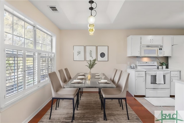 dining area featuring light hardwood / wood-style floors and a raised ceiling