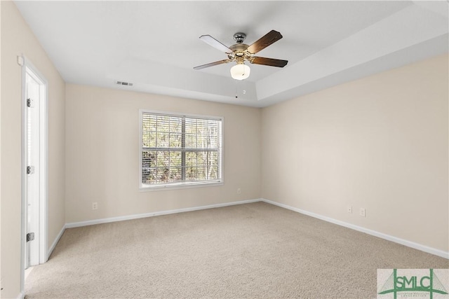 carpeted empty room with a raised ceiling and ceiling fan