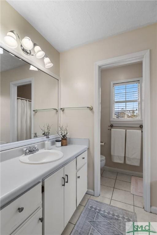 bathroom with tile patterned flooring, vanity, a textured ceiling, and toilet