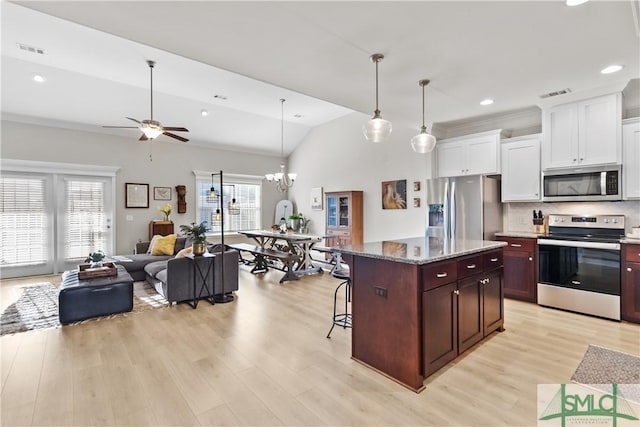 kitchen featuring a kitchen island, a kitchen breakfast bar, open floor plan, appliances with stainless steel finishes, and decorative light fixtures