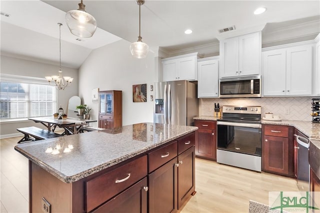 kitchen with appliances with stainless steel finishes, pendant lighting, and white cabinets