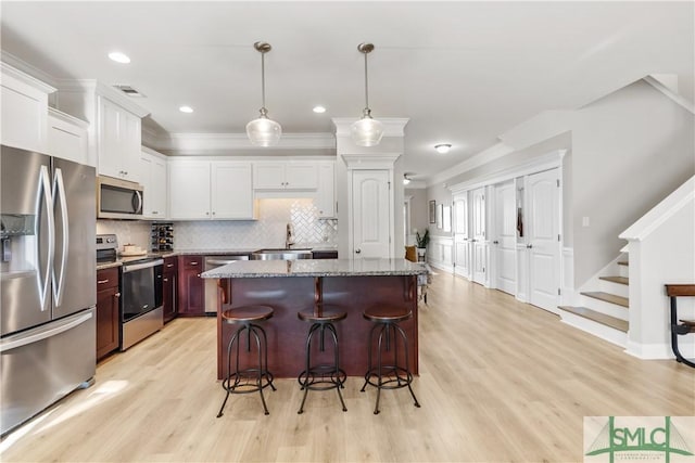 kitchen featuring hanging light fixtures, appliances with stainless steel finishes, a breakfast bar area, and a kitchen island