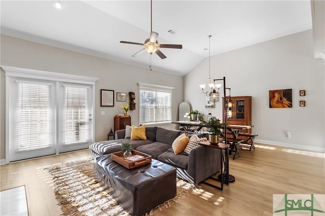 living area featuring lofted ceiling, light wood finished floors, baseboards, and visible vents