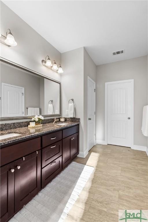 bathroom with double vanity, baseboards, visible vents, and a sink