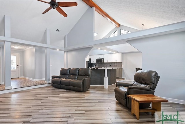 living room with beamed ceiling, ceiling fan, high vaulted ceiling, and light hardwood / wood-style floors