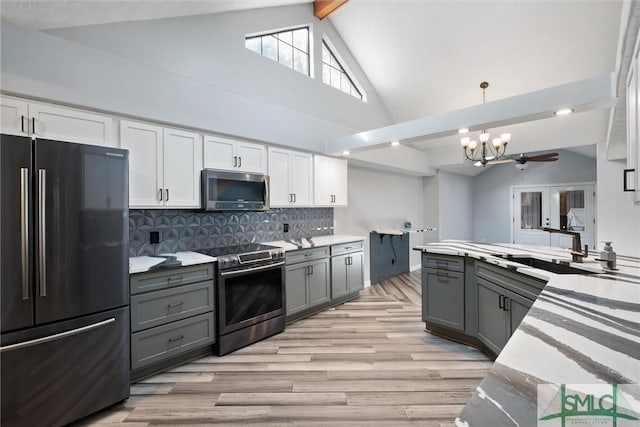 kitchen with gray cabinets, pendant lighting, white cabinets, backsplash, and stainless steel appliances