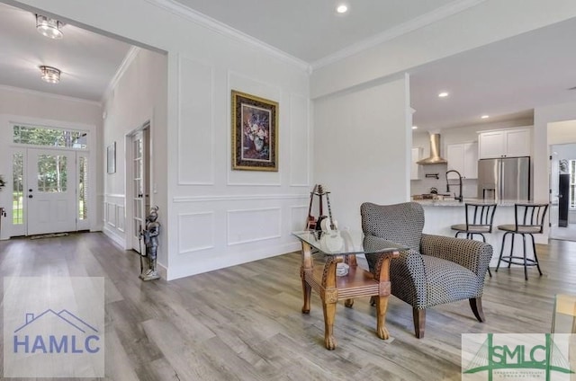 living area with crown molding and light hardwood / wood-style floors