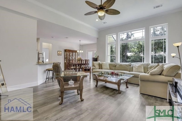 living room featuring ceiling fan with notable chandelier, ornamental molding, and hardwood / wood-style floors