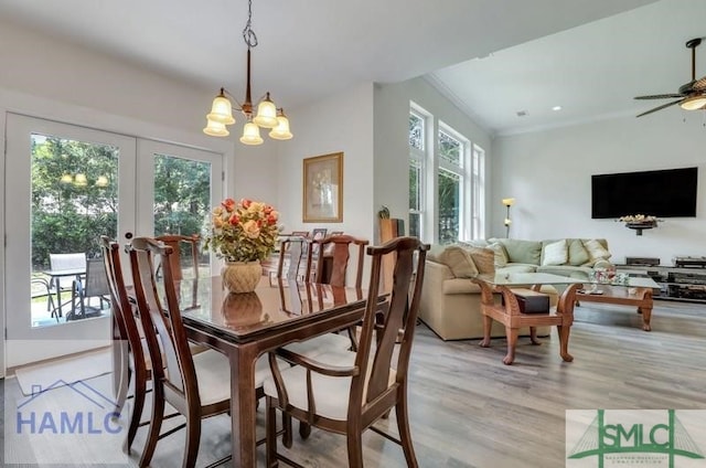 dining space featuring french doors, ceiling fan with notable chandelier, and light wood-type flooring