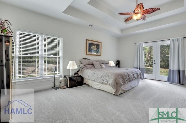 bedroom featuring access to exterior, a tray ceiling, french doors, and carpet