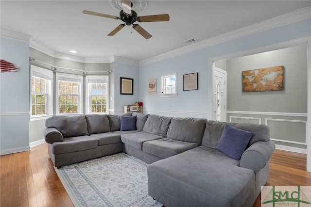 living room featuring hardwood / wood-style flooring, ornamental molding, and ceiling fan