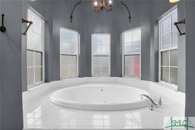 bathroom with a relaxing tiled tub and a notable chandelier