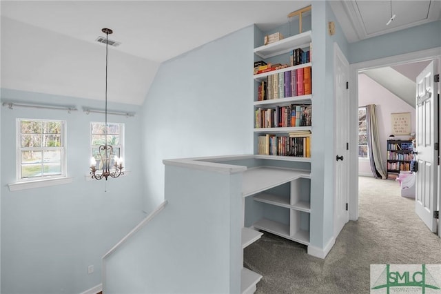 hall with lofted ceiling, carpet floors, and a notable chandelier