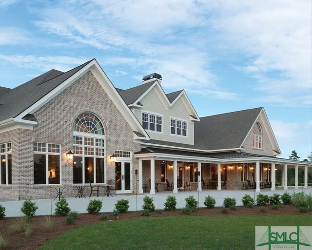 rear view of property featuring french doors, a patio, and a lawn