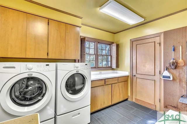 clothes washing area with cabinets, crown molding, and washer and dryer