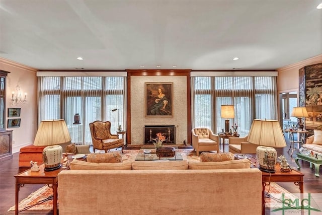 living room featuring wood-type flooring, ornamental molding, and a healthy amount of sunlight