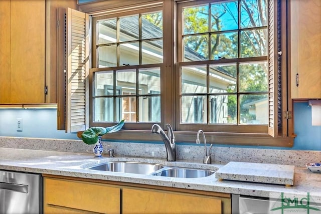 kitchen featuring dishwasher, sink, and light stone countertops