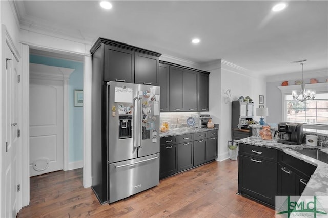 kitchen featuring stainless steel refrigerator with ice dispenser, ornamental molding, wood-type flooring, and light stone counters