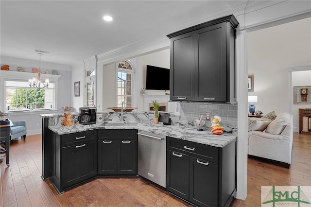 kitchen with tasteful backsplash, dishwasher, sink, and light hardwood / wood-style floors