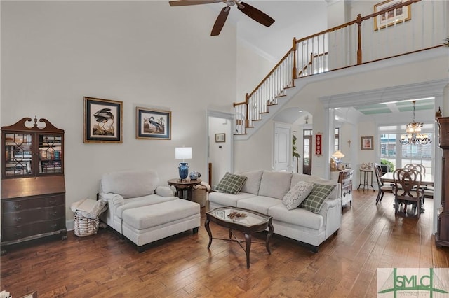 living room with a towering ceiling, dark hardwood / wood-style floors, and ceiling fan with notable chandelier