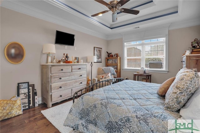 bedroom featuring crown molding, a tray ceiling, dark wood-type flooring, and ceiling fan