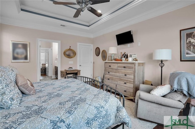 bedroom with connected bathroom, crown molding, a raised ceiling, and ceiling fan