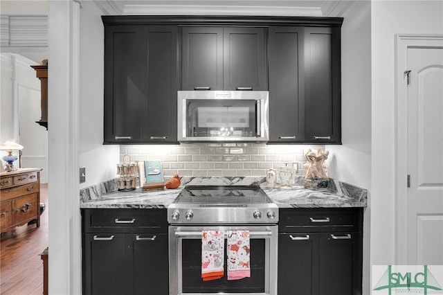 kitchen with appliances with stainless steel finishes, hardwood / wood-style floors, tasteful backsplash, light stone counters, and crown molding