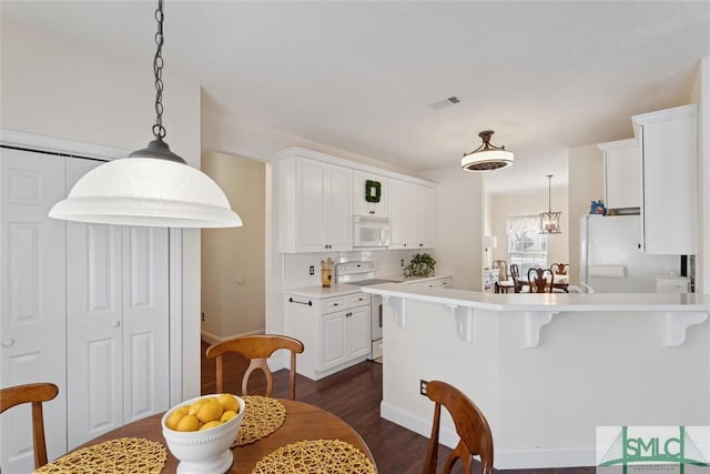 kitchen with hanging light fixtures, dark wood-type flooring, white cabinets, and white appliances