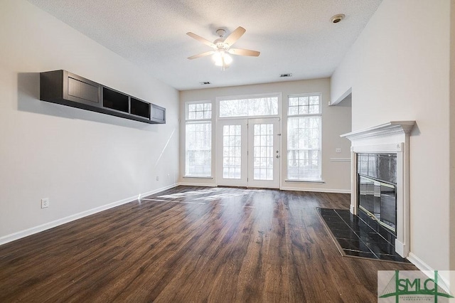 unfurnished living room featuring a premium fireplace, dark wood-type flooring, ceiling fan, and a textured ceiling