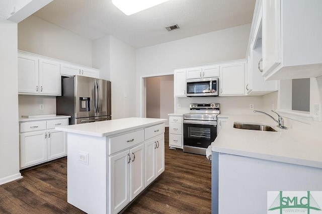 kitchen featuring stainless steel appliances, a center island, sink, and white cabinets