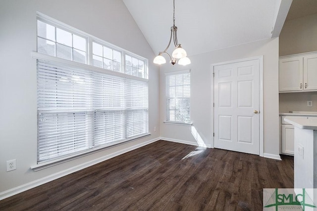 unfurnished dining area featuring vaulted ceiling, dark hardwood / wood-style floors, and a chandelier