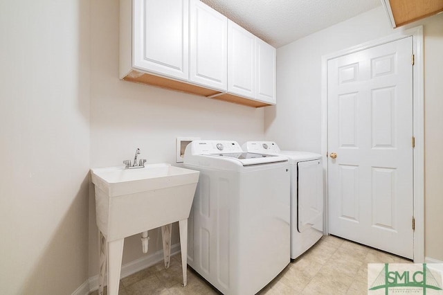 clothes washing area with cabinets, washing machine and dryer, and a textured ceiling