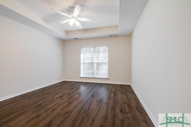 unfurnished room featuring ceiling fan, wood-type flooring, a tray ceiling, and a textured ceiling