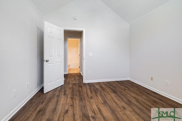 spare room featuring lofted ceiling and dark wood-type flooring