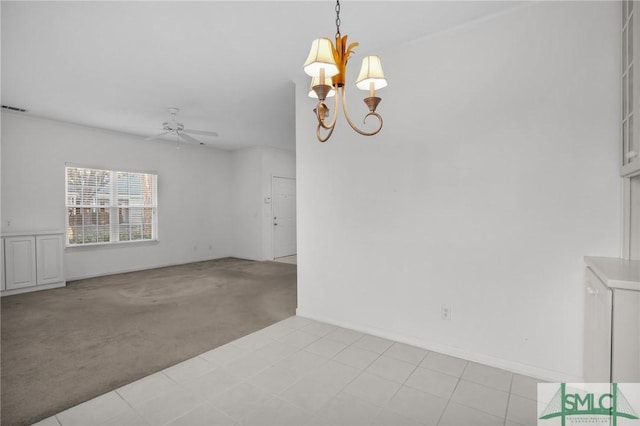 carpeted spare room with ceiling fan with notable chandelier