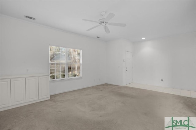 spare room with crown molding, light carpet, and ceiling fan