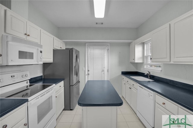 kitchen featuring white cabinetry, a center island, sink, and white appliances