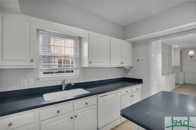 kitchen featuring white dishwasher, sink, and white cabinets