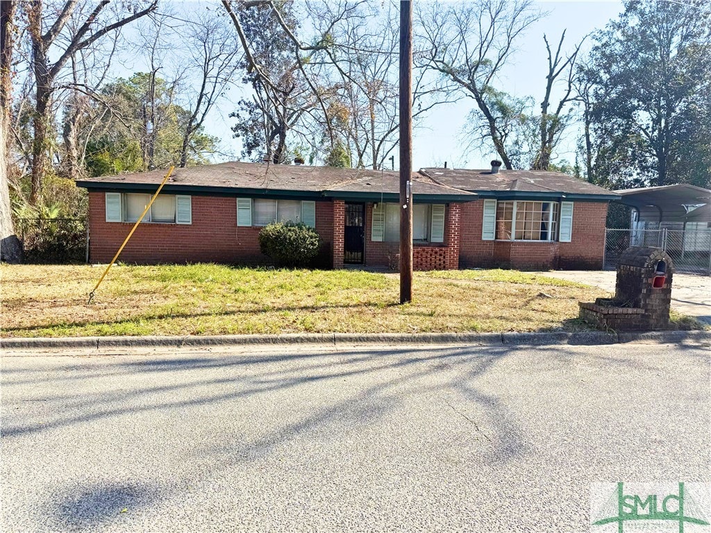 ranch-style house featuring a carport and a front yard