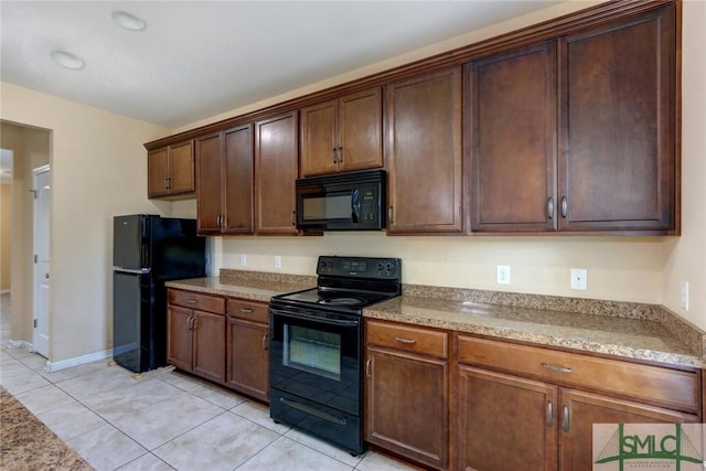 kitchen featuring light stone countertops, light tile patterned floors, and black appliances