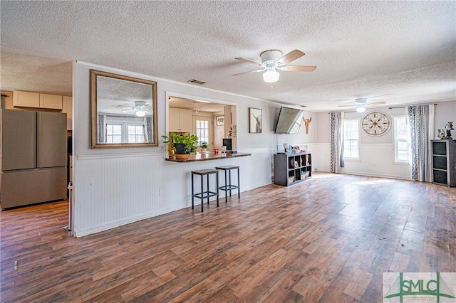 living room featuring ceiling fan, dark hardwood / wood-style floors, and a textured ceiling